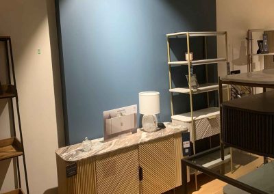 Painted feature wall in blue and neutral tones behind a homeware room set display in NEXT store