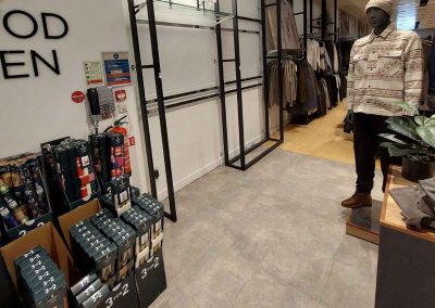 New grey stone-effect flooring and black metal clothing racking installed in NEXT menswear department