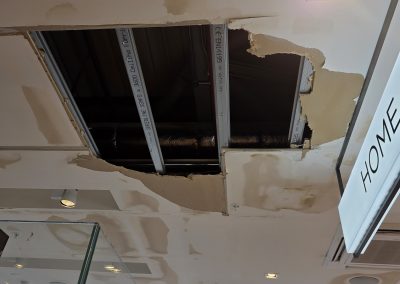 Exposed ceiling void with water-damaged plasterboard stripped back in NEXT store, Eastbourne