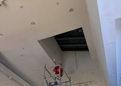 Decorator on scaffold tower painting high-level ceiling inside NEXT store