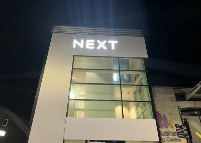 Rendered NEXT store facade illuminated at night with glowing sign