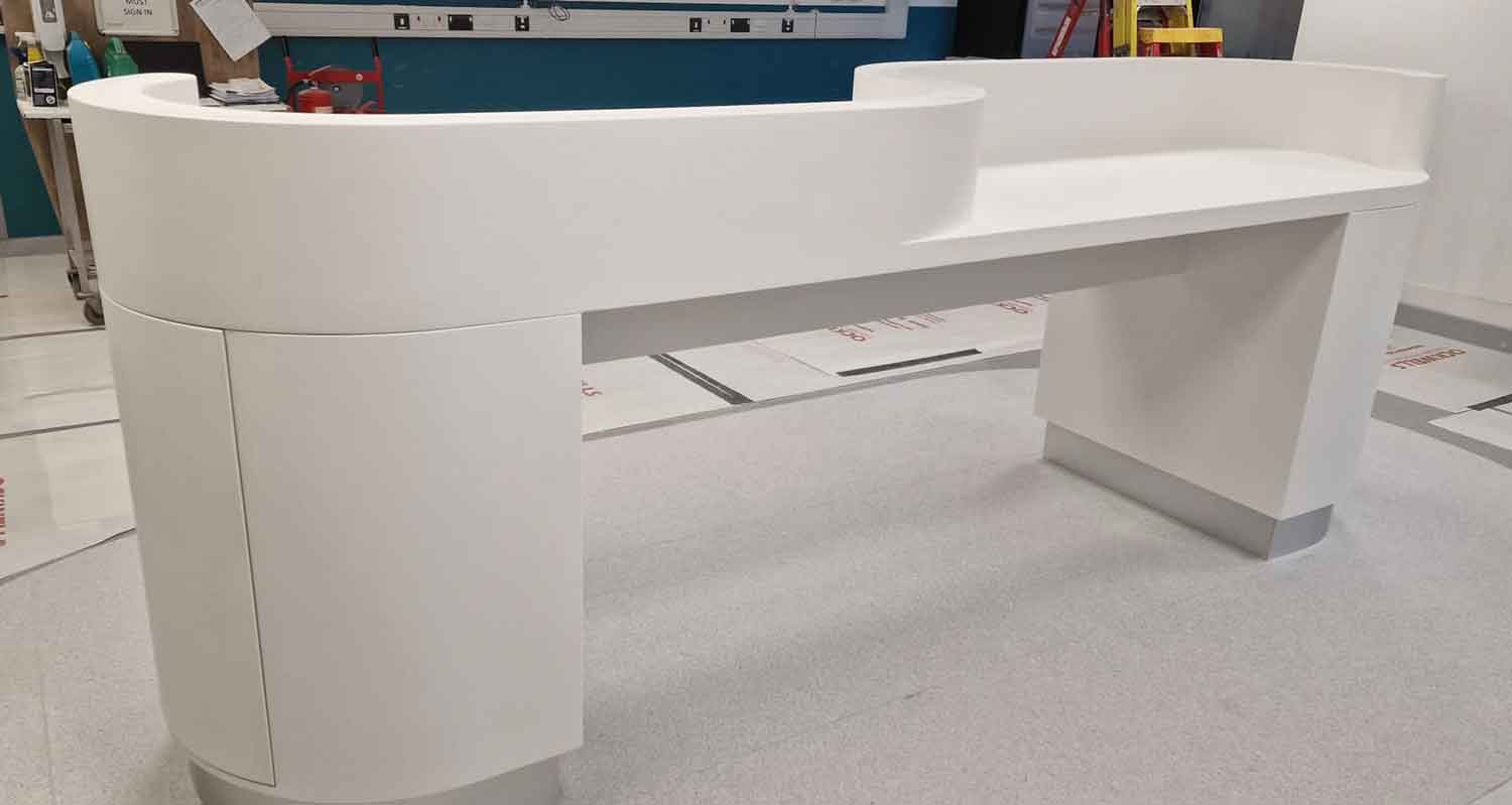 Curved white solid-surface retail checkout counter with lowered accessible service point, manufactured and installed by Central Shop Maintenance