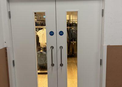 Completed BMTrada-certified fire door set fitted by CSM at Next, Oxford Street, London, with vision panels, kick plates and self-closers