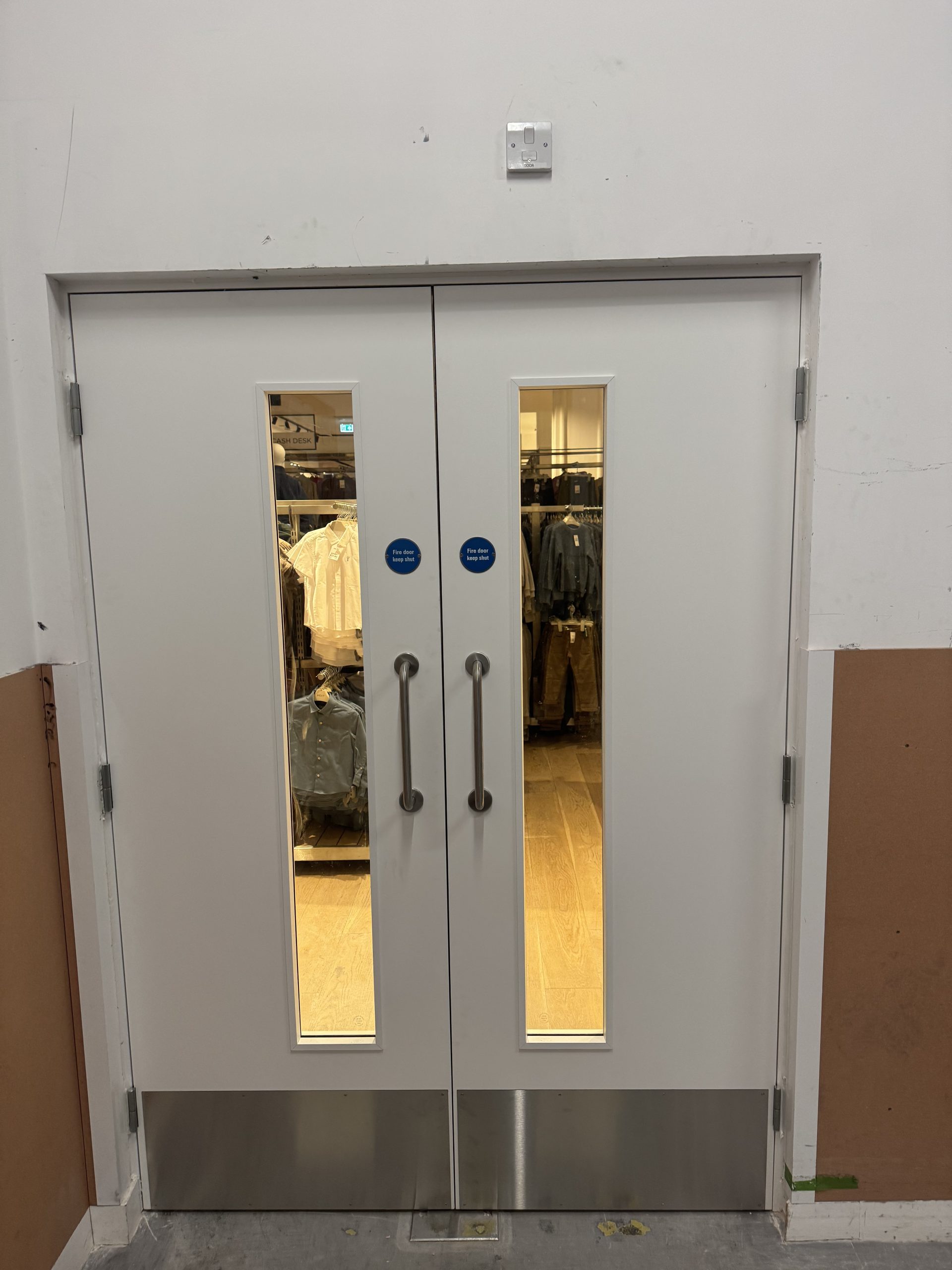 Completed BMTrada-certified fire door set fitted by CSM at Next, Oxford Street, London, with vision panels, kick plates and self-closers